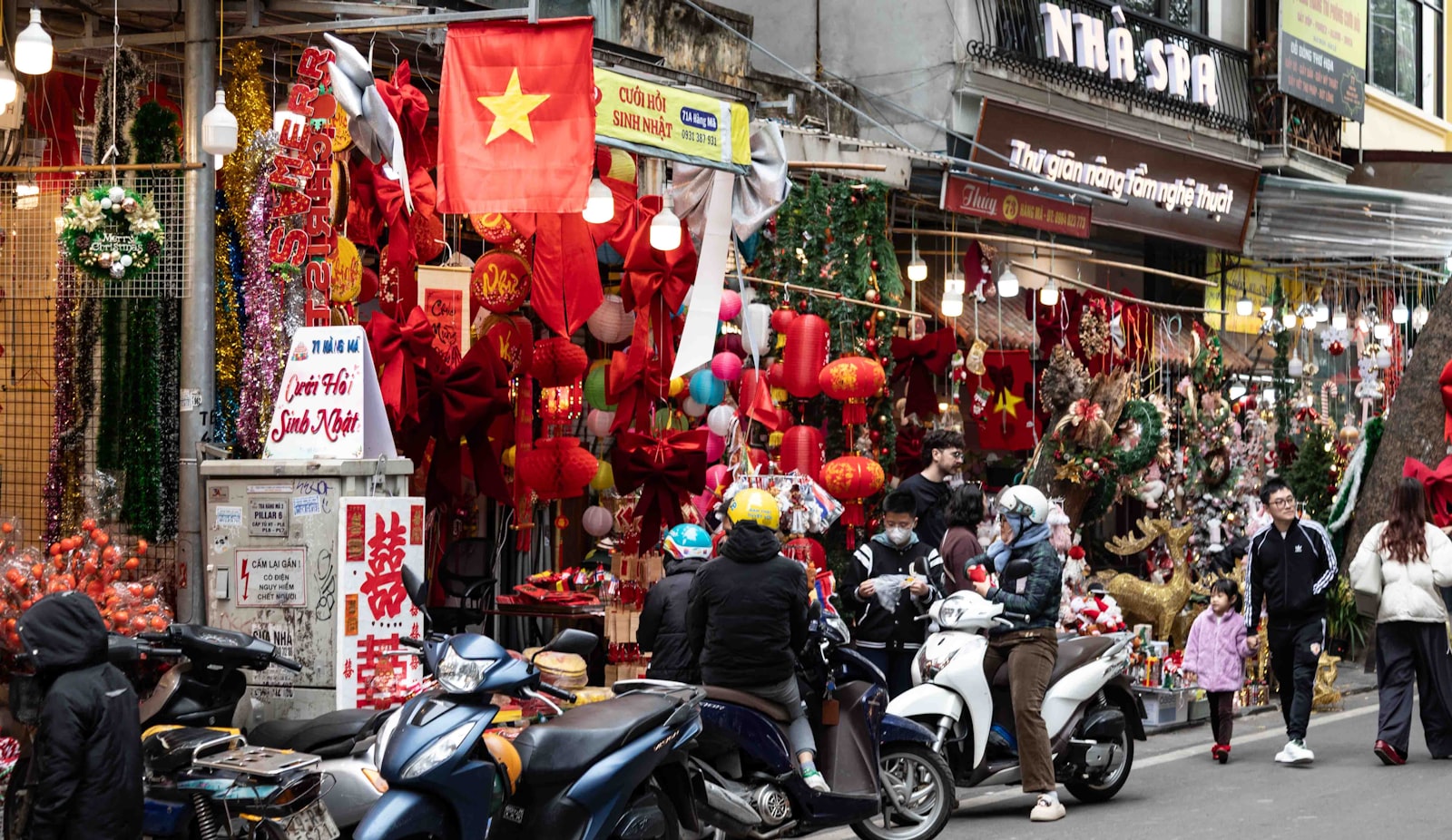 A crowded retail street in Vietnam lined with shopfronts and shoppers on motorbikes