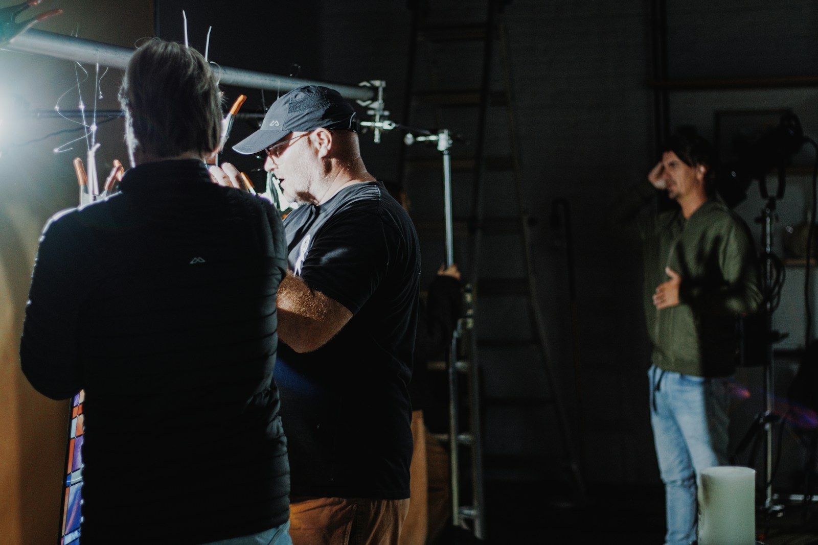 A film crew setting up lights and camera support on a darkened production set