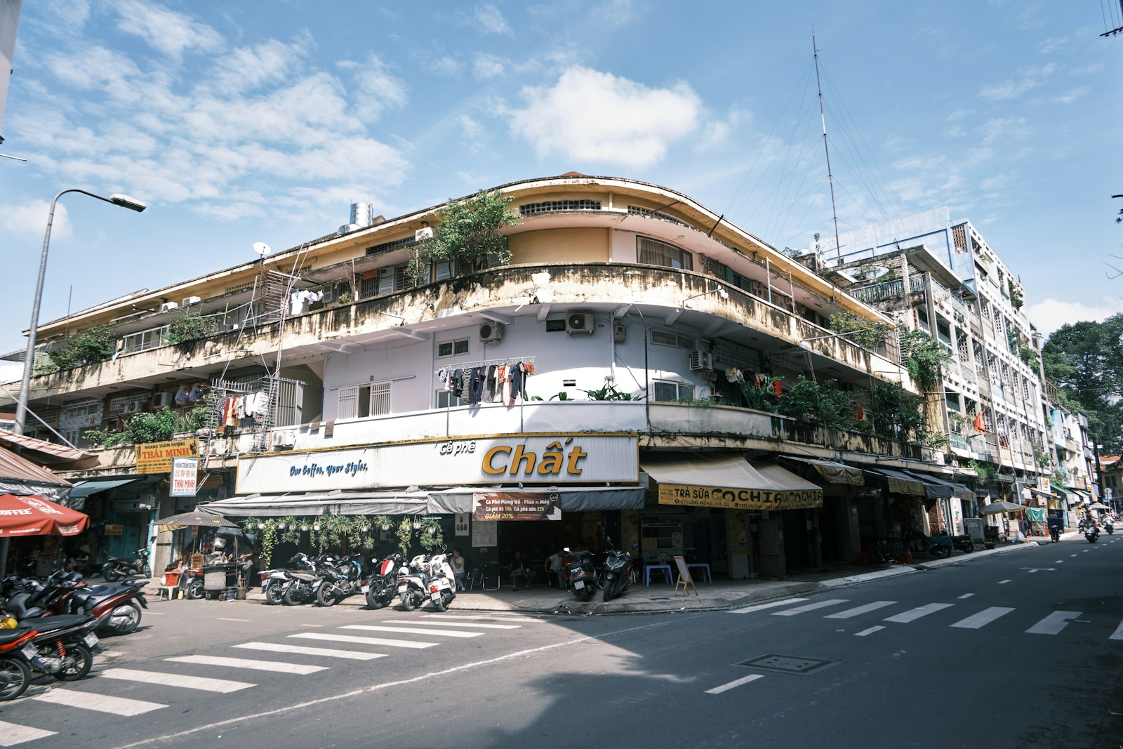 A curved period apartment block with street level shops and parked motorbikes in Ho Chi Minh City